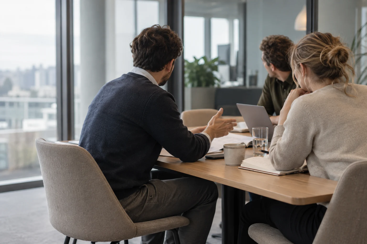 Drie anonieme collega's bespreken een document in een kantoor met koel daglicht.